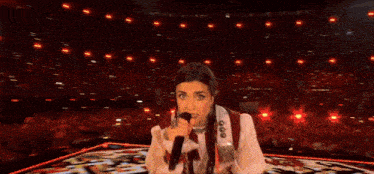 a woman is singing into a microphone on a stage