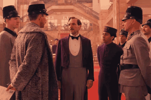 a man in a tuxedo stands in front of a group of men wearing hats with the letter a on them
