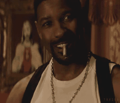a man with a beard wearing a white tank top and a gold chain around his neck