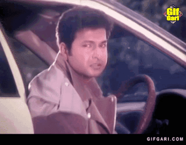 a man sitting in a car with a gifgari.com logo on the bottom