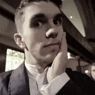 a man in a suit and tie is holding his hand to his face .