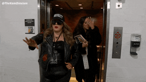 a woman wearing a hat that says security is standing in an elevator