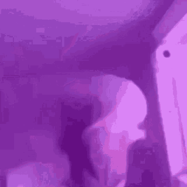 a person is standing in a room with purple lights and a purple background .