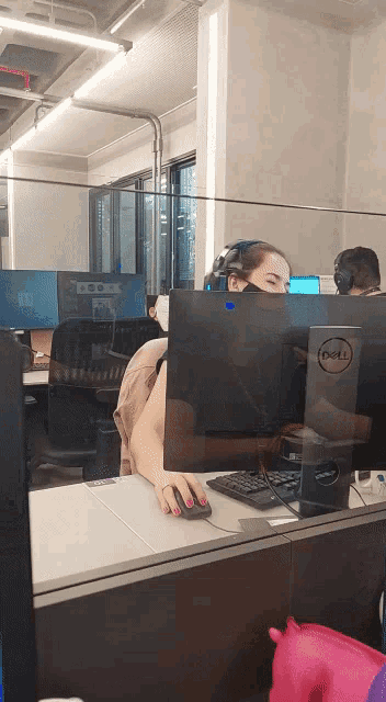 a woman wearing a mask sits at a dell computer