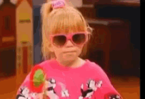 a little girl wearing sunglasses and a pink shirt is holding a toy gun
