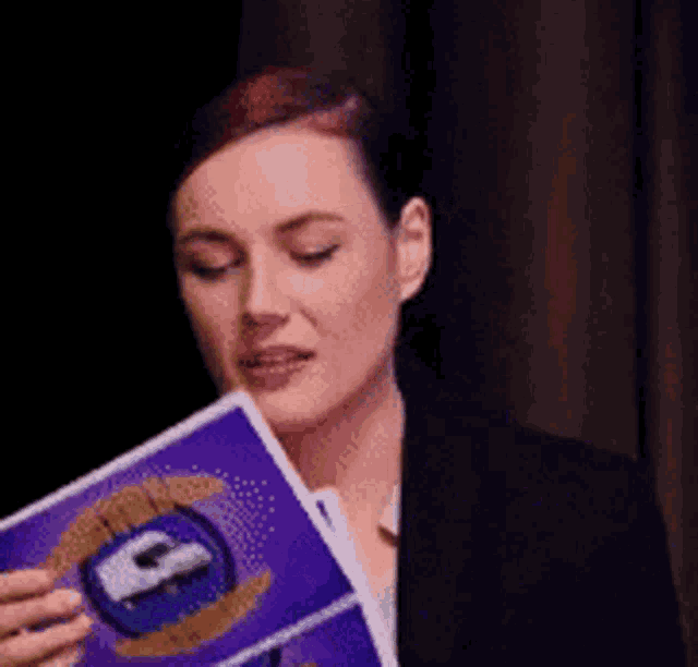 a woman in a suit is holding a purple book with a picture of a car on it .