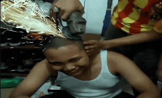 a man is being shaved by another man with a grinder
