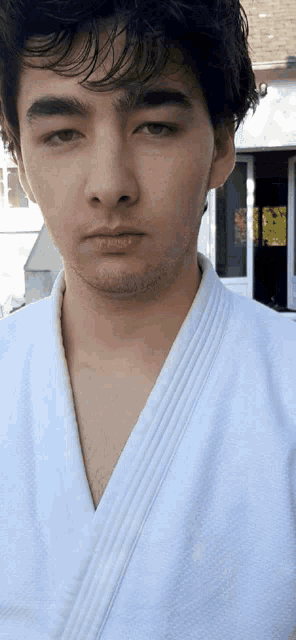 a young man wearing a white karate uniform is looking at the camera