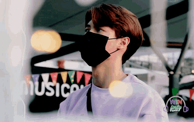 a man wearing a face mask is standing in front of a sign that says music