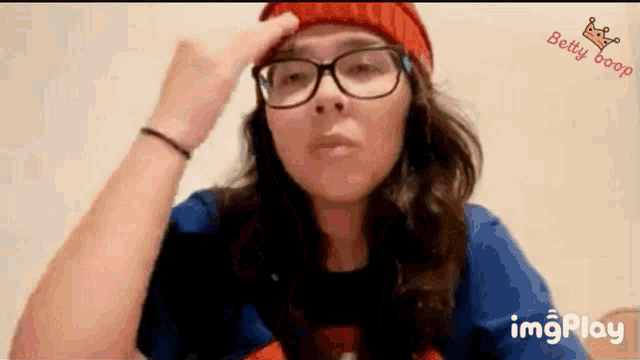 a woman wearing glasses and a red hat is making a funny face while using imgplay app