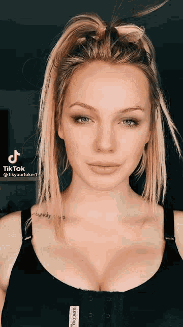 a woman wearing a black bra and a ponytail looks at the camera .