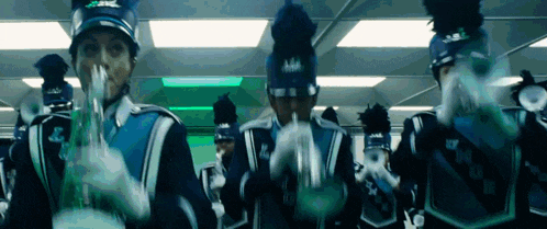 a marching band is playing their instruments in a room with a green light