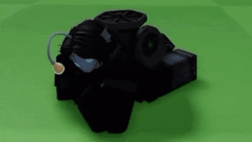 a black robot with a microphone on its head is sitting on a green field .