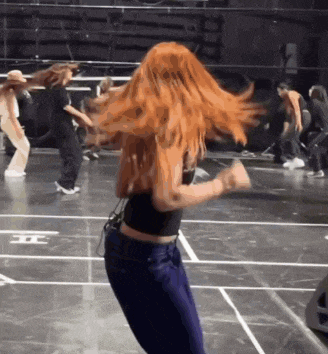 a woman with red hair is dancing on a stage with other dancers .