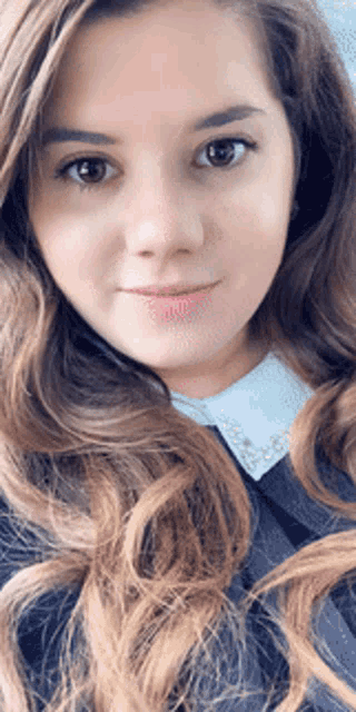 a close up of a woman 's face with long brown hair and a white collar