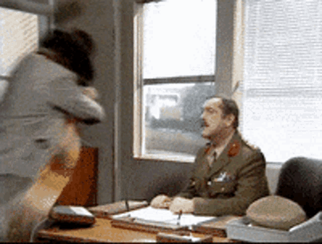 a man in a military uniform sits at a desk