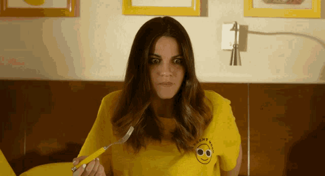 a woman wearing a yellow shirt that has a smiley face on it