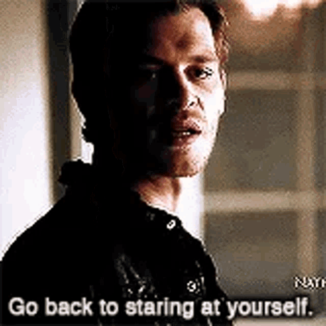 a man is standing in a dark room and talking to himself .