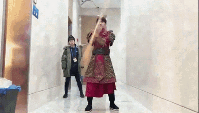 a man in a costume is standing in a hallway holding a sword .