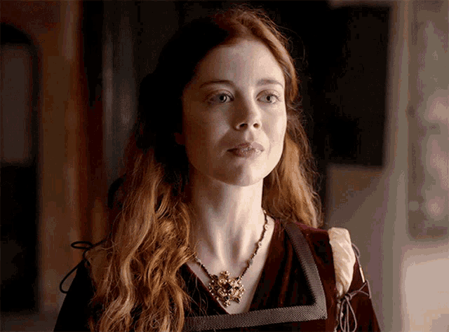 a woman with red hair wearing a necklace and a red dress