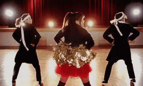 a cheerleader in a red skirt is surrounded by other cheerleaders