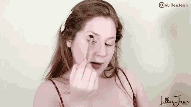 a woman is applying eye shadow with a brush .