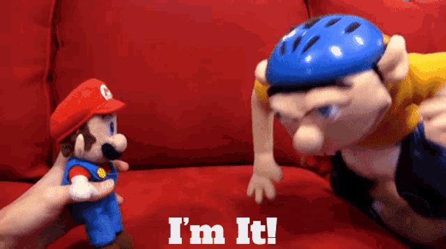 a stuffed mario and a stuffed jeff are on a red couch with the words i 'm it