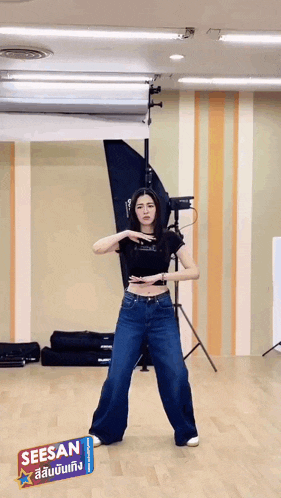 a woman is dancing in a room with a sign that says seesan on it .