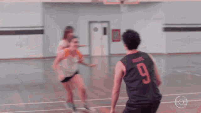 a man with the number 9 on his jersey is playing basketball with two women