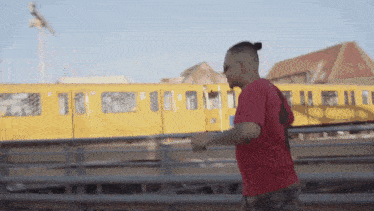 a man in a red shirt is running in front of a train