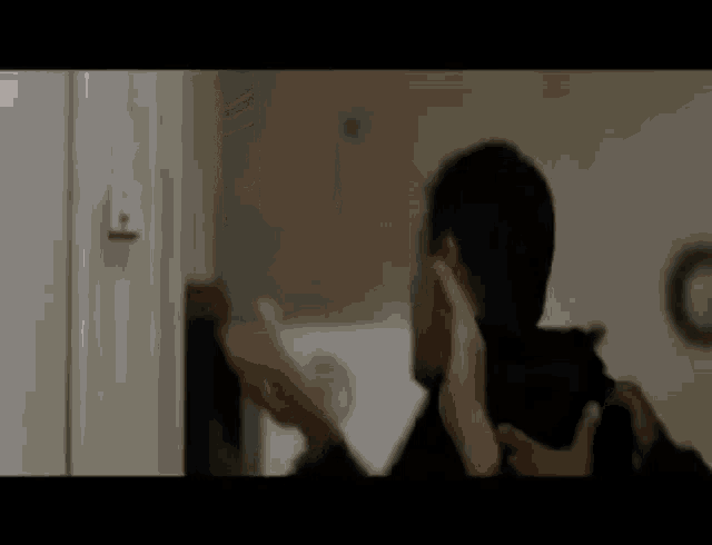 a man is standing in front of a door with his hands on his face .