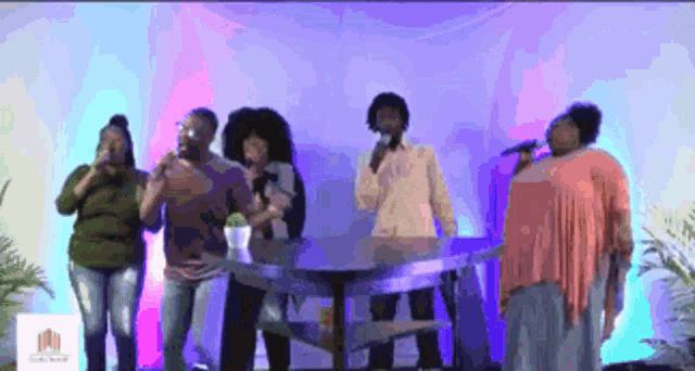 a group of people singing into microphones in front of a sign that says grace house