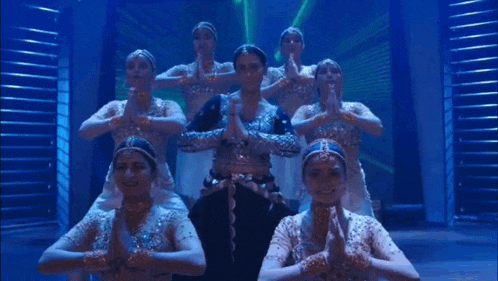 a group of women are performing a dance on a stage in front of a blue light .