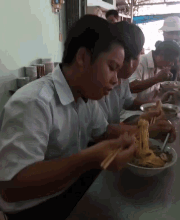 a man in a white shirt is eating noodles with chopsticks