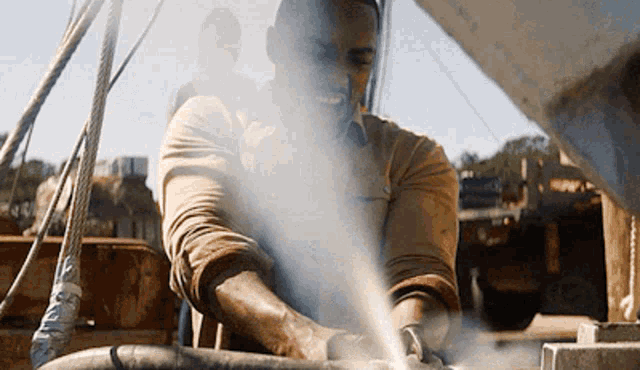 a man in a tan shirt is spraying a hose