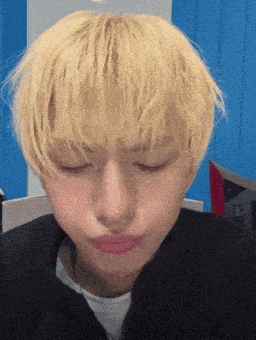 a young man with blonde hair is making a funny face with his eyes closed