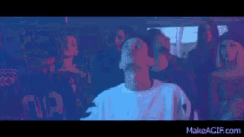 a woman in a white sweater is dancing in front of a crowd of people ..