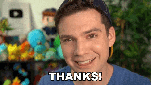 a man in a blue shirt says thanks in front of a bunch of stuffed animals