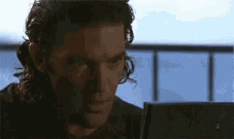 a man with curly hair is looking at a computer screen