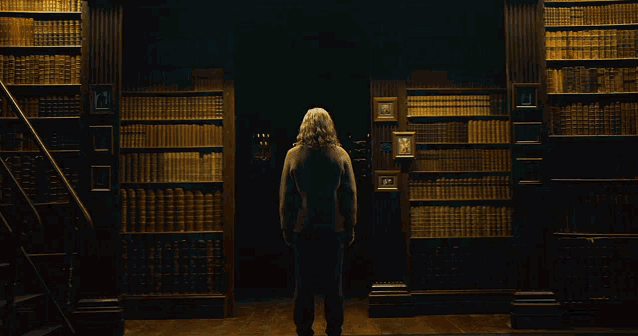 a man stands in a library with a staircase and shelves full of books including one with the number 13 on it