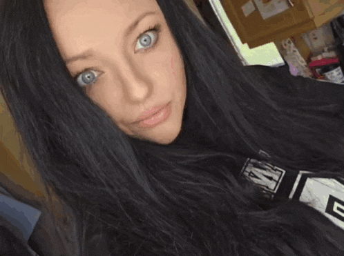 a woman with long black hair is giving a thumbs up sign