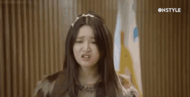 a young woman with long hair is making a funny face while standing in front of a flag .