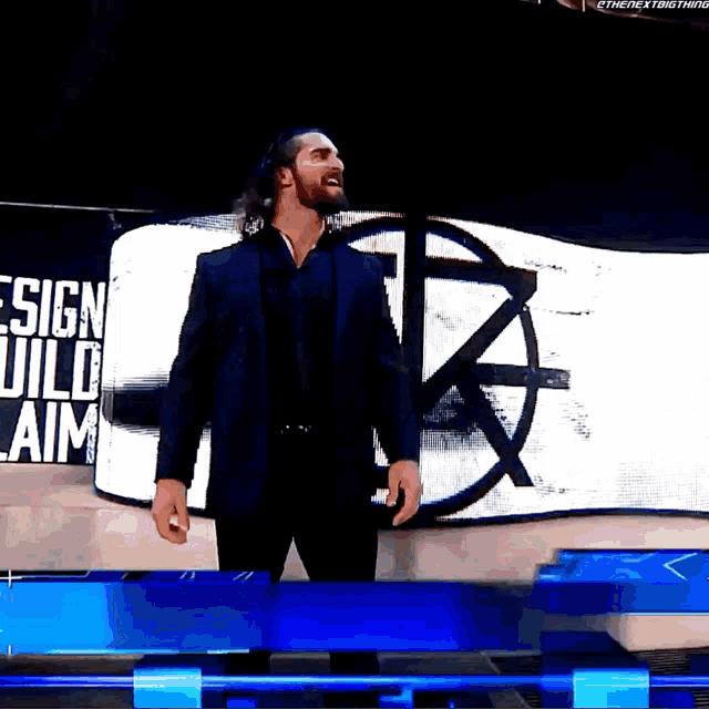 a man in a suit is standing in front of a sign that says " design wild aim "
