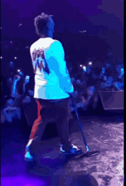 a man is standing on a stage with a microphone and a shirt that says ' shawn ' on the back of it