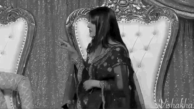 a black and white photo of a woman sitting in a chair with the name vishakha at the bottom