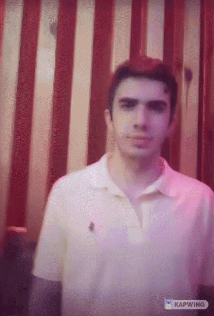 a man in a white polo shirt is standing in front of a red and yellow wall