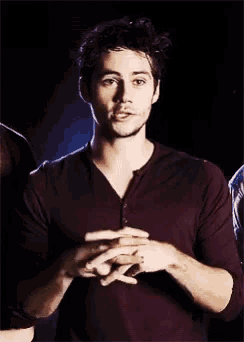 a man in a purple shirt is holding his hands together