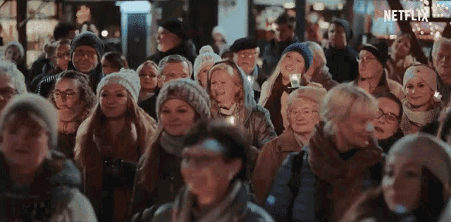 a large group of people are standing in a crowd on a street at night .