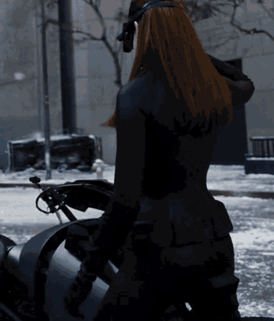 a woman in a black suit is sitting on a motorcycle in the snow
