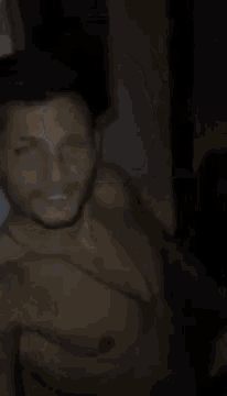 a man without a shirt is taking a selfie with his hands in front of his face .